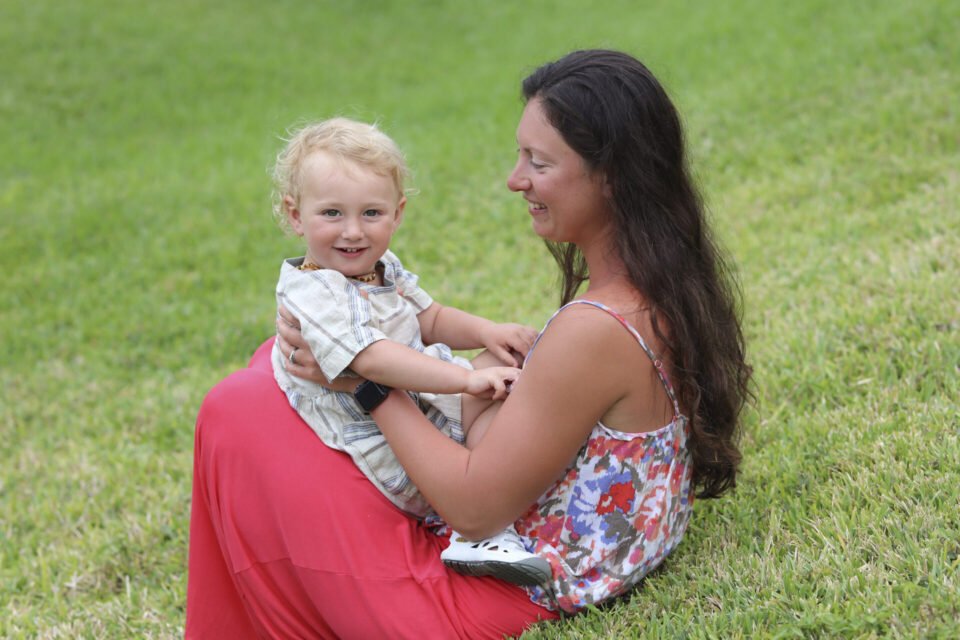 Mom and child sitting on the green lawn in Naples Park. Photo by Katrina Photography